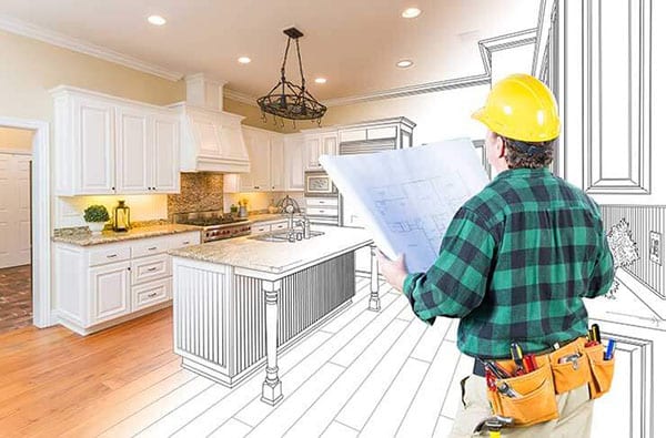 Kitchen Remodeling - Photo of a remodeling contractor with a set of plans in his hands with his vision in the background of what the kitchen will look like when finished. 
