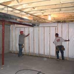 Basement Remodel - Photo of a stud wall being built by two Tamer Construction employees in basement.